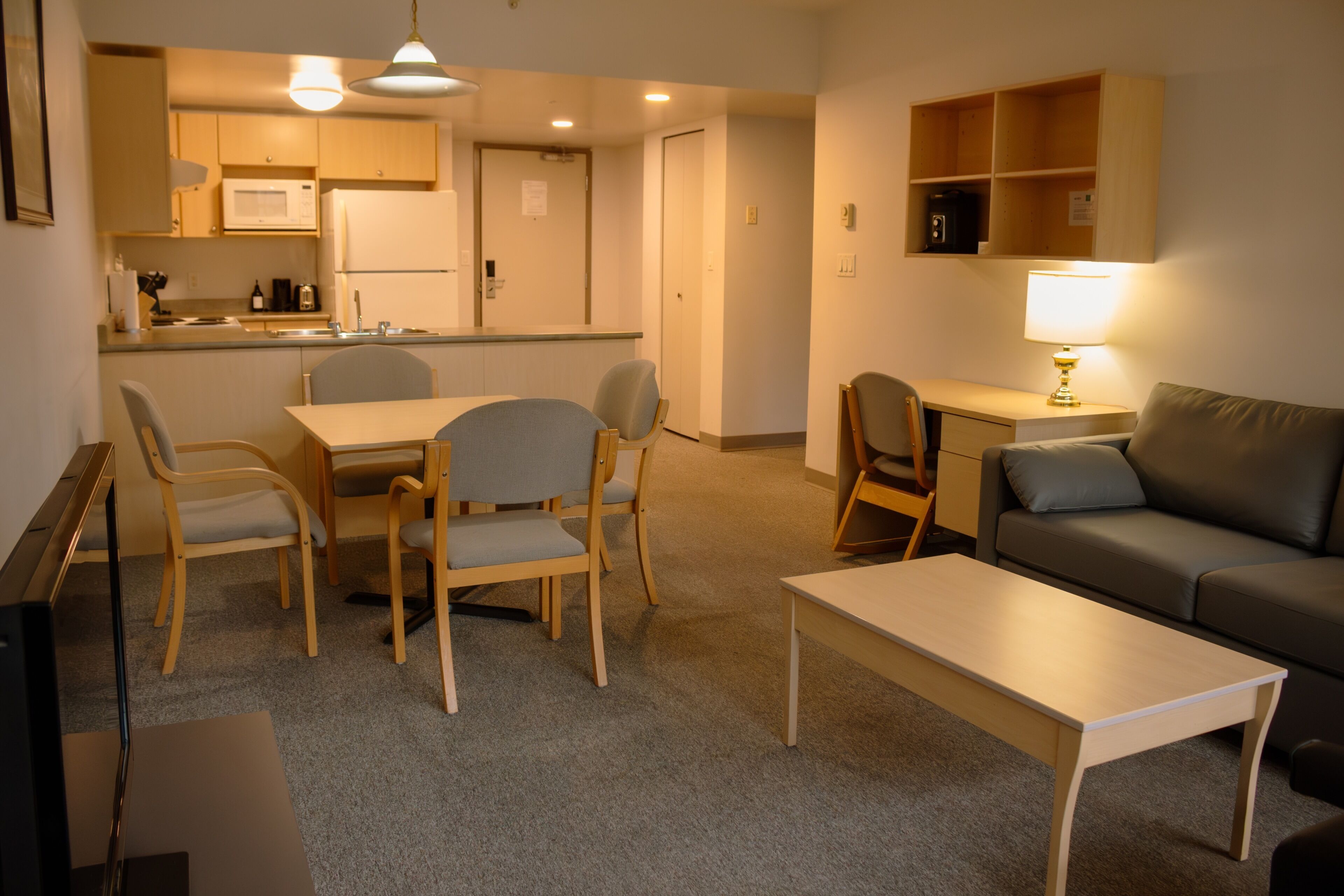 A compact living space with a dining area, a sofa, a coffee table, and a kitchenette.