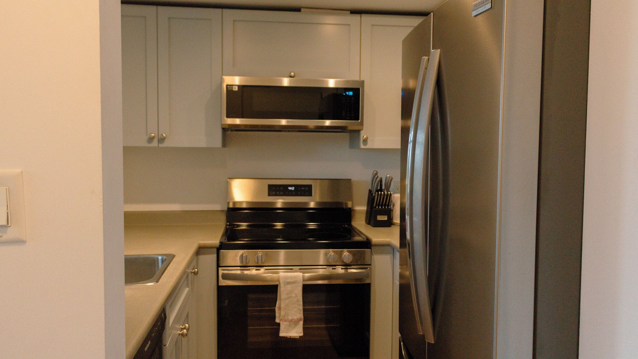 Cocina compacta con microondas, horno y refrigerador de acero inoxidable.