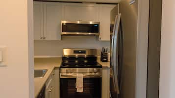 Cocina compacta con microondas, horno y refrigerador de acero inoxidable.