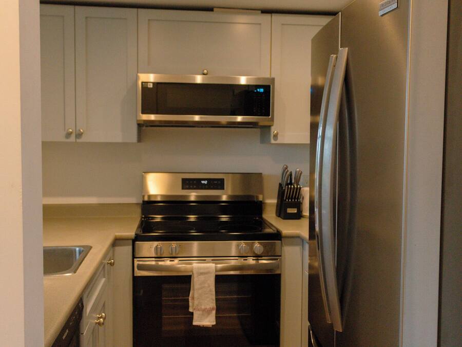 Cocina compacta con microondas, horno y refrigerador de acero inoxidable.