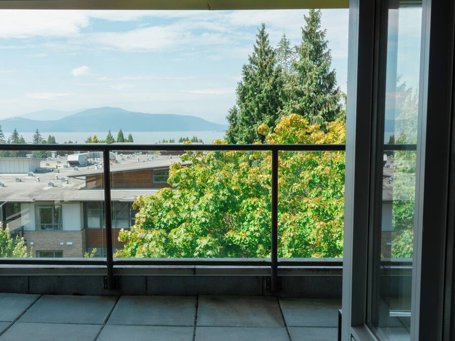 A balcony with a view of a cityscape, including buildings and a body of water.