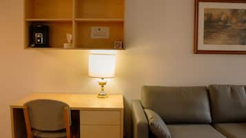 Una habitación con escritorio, silla y sofá.