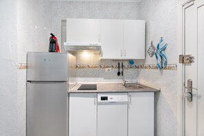 A compact kitchen with a refrigerator, dishwasher, and a sink.