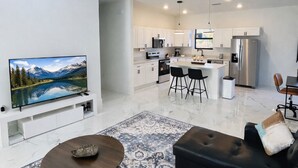 A modern living room with a flat-screen TV, a coffee table, a patterned rug, and a black sofa. - Casa encanto, your home away from home. (Lehigh Acres)