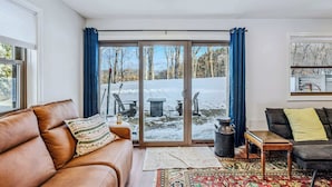 A cozy living room with a brown leather sofa, a patterned throw pillow, a wooden coffee table, and a rug. - Sunny Condo with Golf Views, Windsor Village (Hartford)