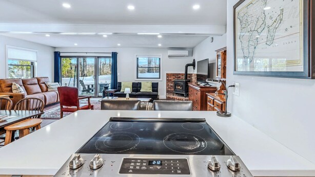 A modern kitchen with a central island, dining area with chairs, a sofa, and a fireplace. - Sunny Condo with Golf Views, Windsor Village (Hartford)
