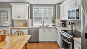 A modern kitchen with white cabinetry, a built-in oven, and a stainless steel refrigerator. - Cozy Collingwood Farmhouse, With Sauna (Collingwood)