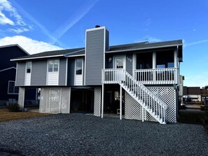 Ein zweistöckiges Haus mit überdachter Veranda, einer Treppe und einer Garage.