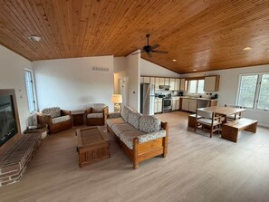 Ein geräumiges Wohnzimmer mit Holzboden, einer Couch, einem Couchtisch und einem Esstisch mit Stühlen.