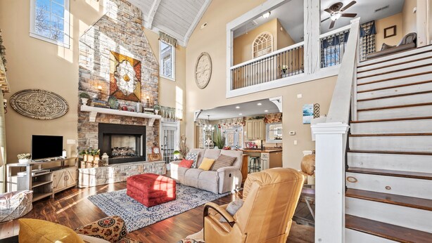 A spacious living room with a fireplace, a high ceiling, and a staircase leading to an upper level. - Lake Views, Gym & Arcade | Gated | Sleeps 9 (Sevierville)