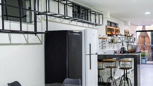 Una cocina moderna con refrigerador, una mesa de vidrio con sillas y una barra con taburetes.
