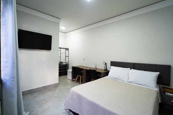 Un dormitorio con cama, escritorio, silla, televisor y armario.