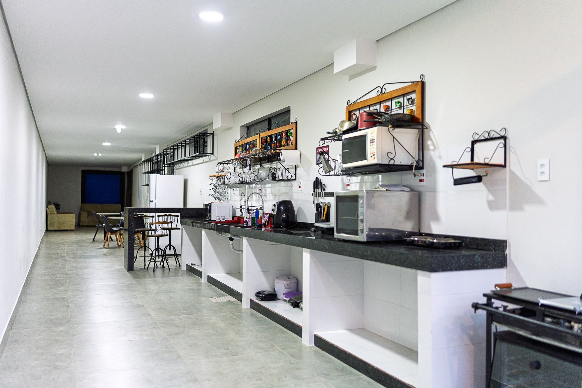 A modern kitchen with built-in appliances, a dining area with bar stools, and a staircase leading to an upper level.