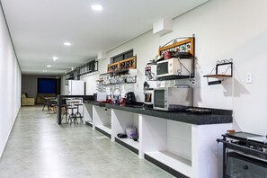 Una cocina moderna con electrodomésticos integrados, una zona de comedor con taburetes altos, y una escalera que conduce a un nivel superior.
