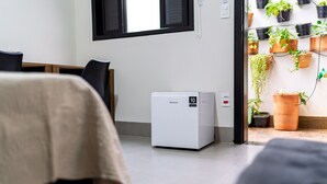 Un equipo de aire acondicionado Hisense compacto en una habitación con una cama, un escritorio y una ventana.