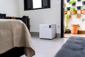 A compact Hisense air conditioner unit in a room with a bed, a desk, and a window.