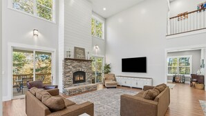 A spacious living room with a fireplace, comfortable seating, and a large TV. - Creekside Luxury Retreat on 22 Acres (Louisville)