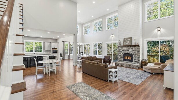 A spacious living area with a fireplace, a dining area, and a kitchen. - Creekside Luxury Retreat on 22 Acres (Louisville)