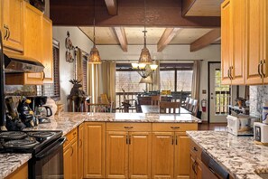 A kitchen with wooden cabinets, a granite countertop, and pendant lighting. - Skyline Ridge • Spectacular Views | Hot Tub | BBQ (Gatlinburg)