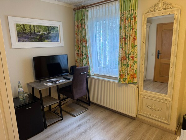 A room with a desk, chair, TV, radiator, and a mirror. - Hotel Wolfsschlucht (Bad Muenstereifel)