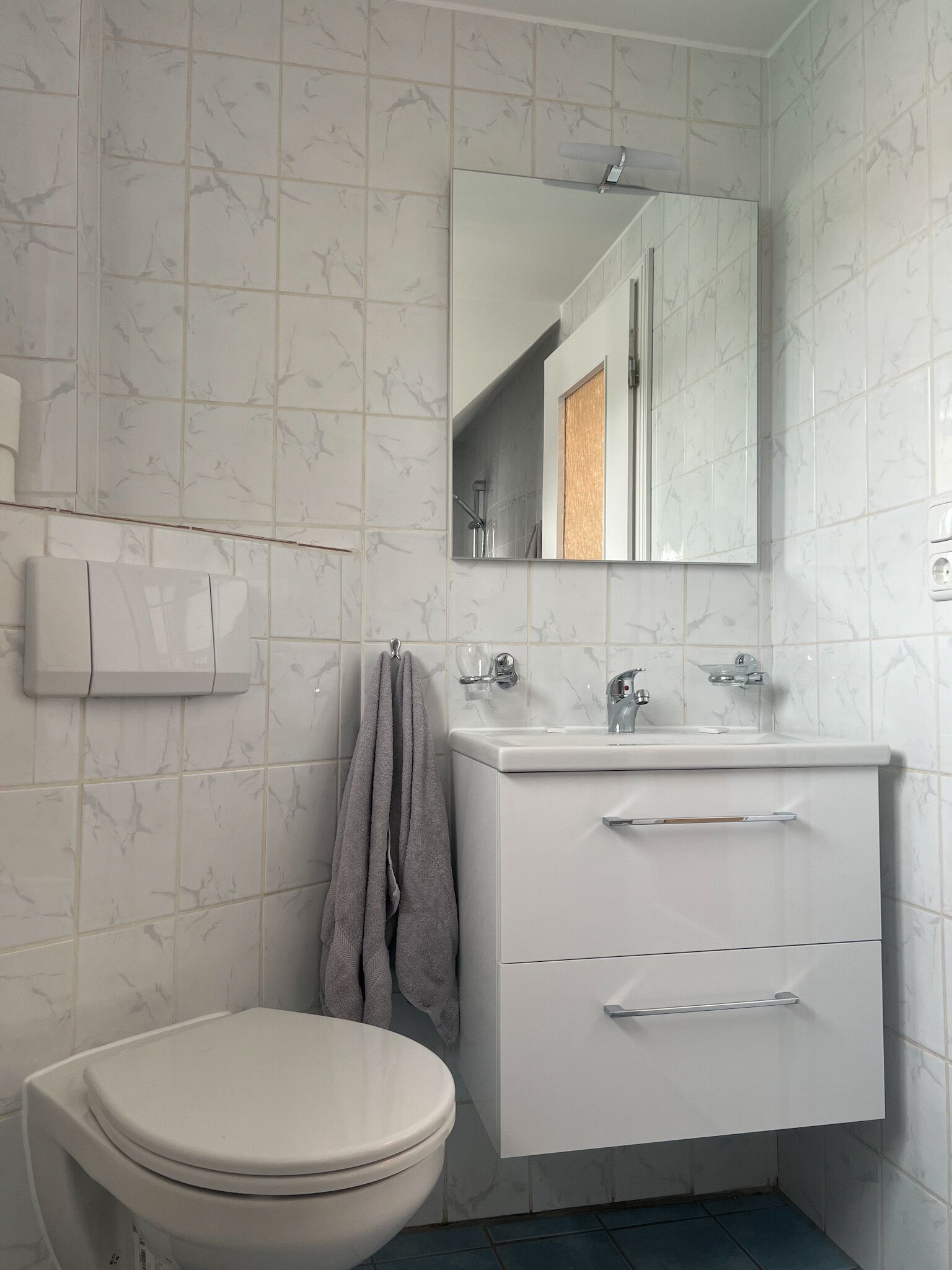 Un bagno moderno con il water, un lavandino, uno specchio e un portasciugamani.