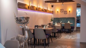Een modern restaurantinterieur met houten vloeren, moderne stoelen en een decoratieve hertenbeeld.