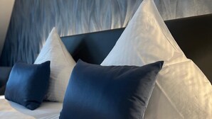 Een bed met witte beddengoed en blauw-witte kussens.