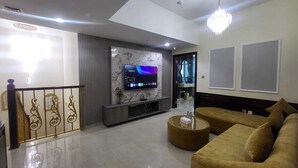 Un salon moderne avec un téléviseur à écran plat, un canapé, une table basse et un lustre.