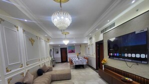 Un salon spacieux avec un grand canapé d’angle, un coin repas avec une table et un téléviseur fixé au mur.