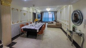 Un coin repas avec une longue table dressée pour six personnes, un canapé et un lustre.