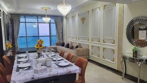 Un coin repas avec une longue table dressée pour six personnes, un canapé et un miroir décoratif.