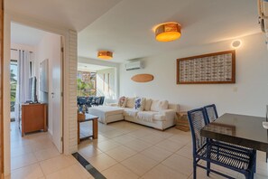 A modern living room with a sofa, a dining table, and a TV.