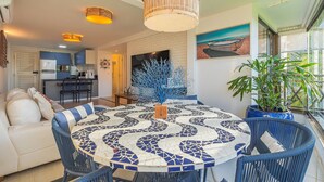 A dining area with a mosaic table, blue chairs, and a ceiling light fixture. - Beach Place #202 - Seafront by Carpediem (Aquiraz)
