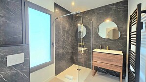 A modern bathroom with a glass shower enclosure, a wooden vanity, and a large mirror. - New Home in Gulf of Morbihan & Vannes, Mahelia (Le Hézo)