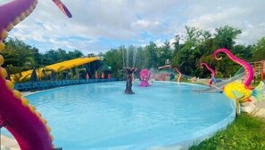 Un parque acuático con piscina, toboganes y estructuras inflables.