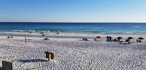 En strand med en träbänk, parasoller och en skylt som visar att det är ett semesterområde.
