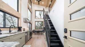 A modern kitchen with a wooden ceiling, a black staircase, and large windows. - The Sun at In the Trees Luxury Resort🌳, Mountaintop, Hot Tub, Fireplace, Full Kitchen (Hot Springs National Park)