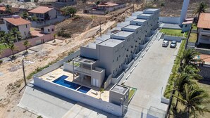 A modern building with a rooftop pool, surrounded by residential areas and a parking lot. - Exclusive Duplex at Beach Townhouse IV by Carpediem (Aquiraz)