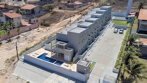 A modern building with a rooftop pool, surrounded by residential areas and a parking lot. - Exclusive Duplex at Beach Townhouse IV by Carpediem (Aquiraz)