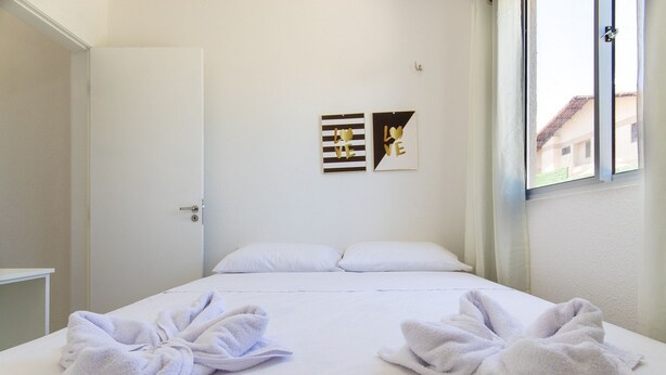 A hotel room with a bed, two towels, and two wall art pieces. - Exclusive Duplex at Beach Townhouse IV by Carpediem (Aquiraz)
