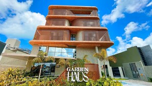A modern building with a unique tiered design, featuring a prominent sign that reads "GARDEN HAUS". - Garden Haus Flats - by Living (João Pessoa)