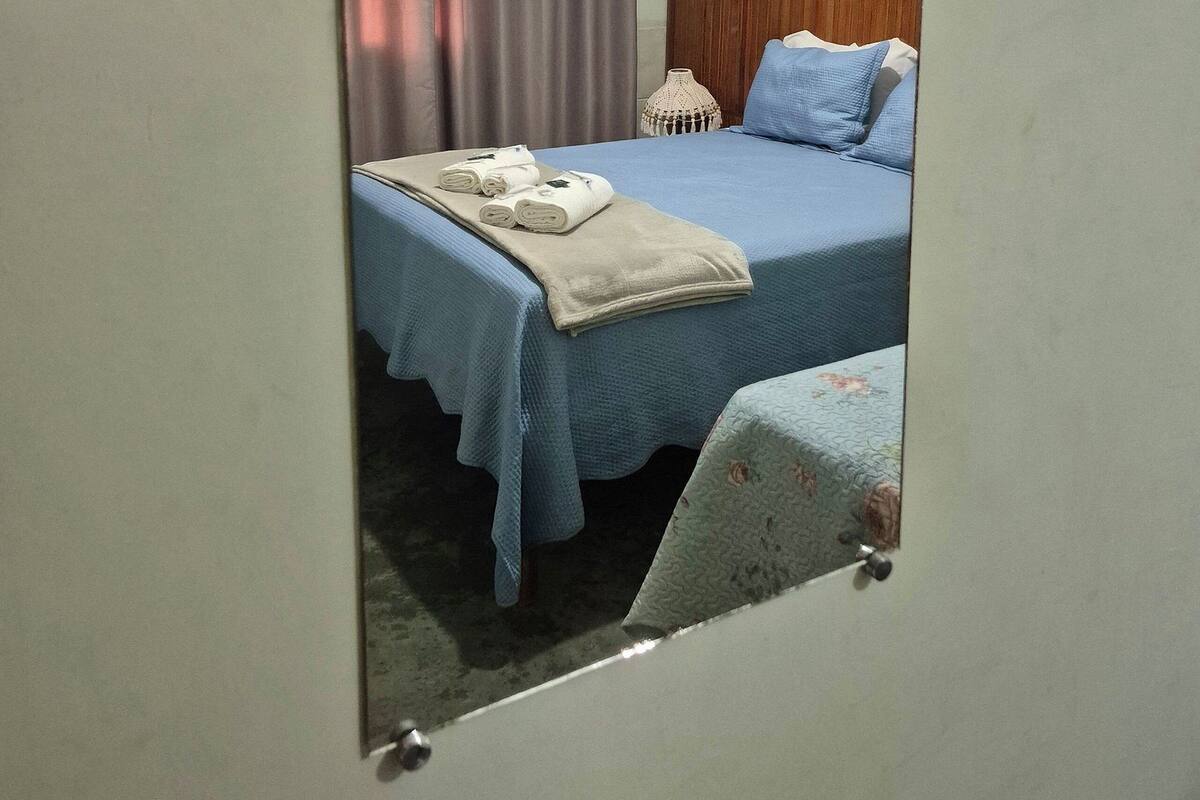 A bedroom with a bed, a nightstand, a mirror, and a ceiling light.
