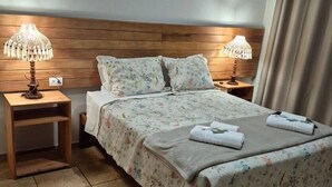 A neatly made bed with floral bedding, two bedside lamps, and a wooden headboard.