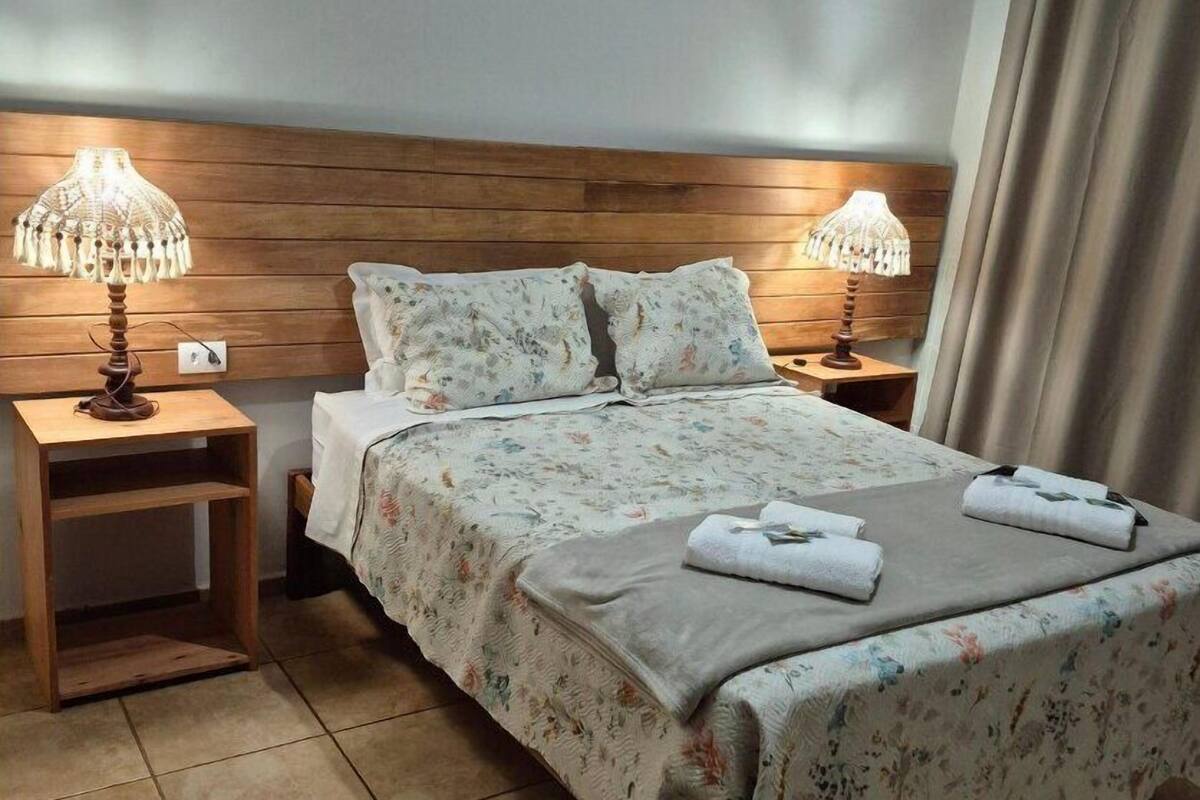 A neatly made bed with floral bedding, two bedside lamps, and a wooden headboard.