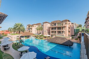 A hotel with a swimming pool, outdoor seating, and palm trees. - Beverly Hills #206 - Luxury Resort by Carpediem (Aquiraz)