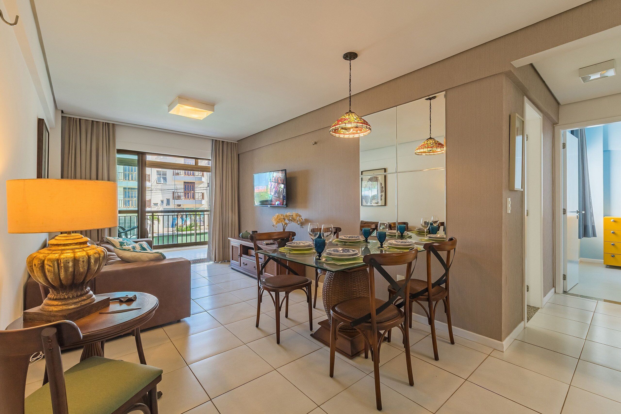 Uma sala de estar moderna com área de jantar, sofá, luminária e TV.