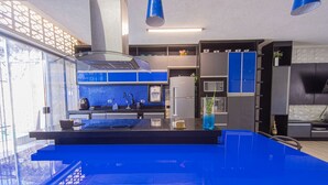 Une cuisine moderne avec des plans de travail bleus, un îlot central et une grande fenêtre.
