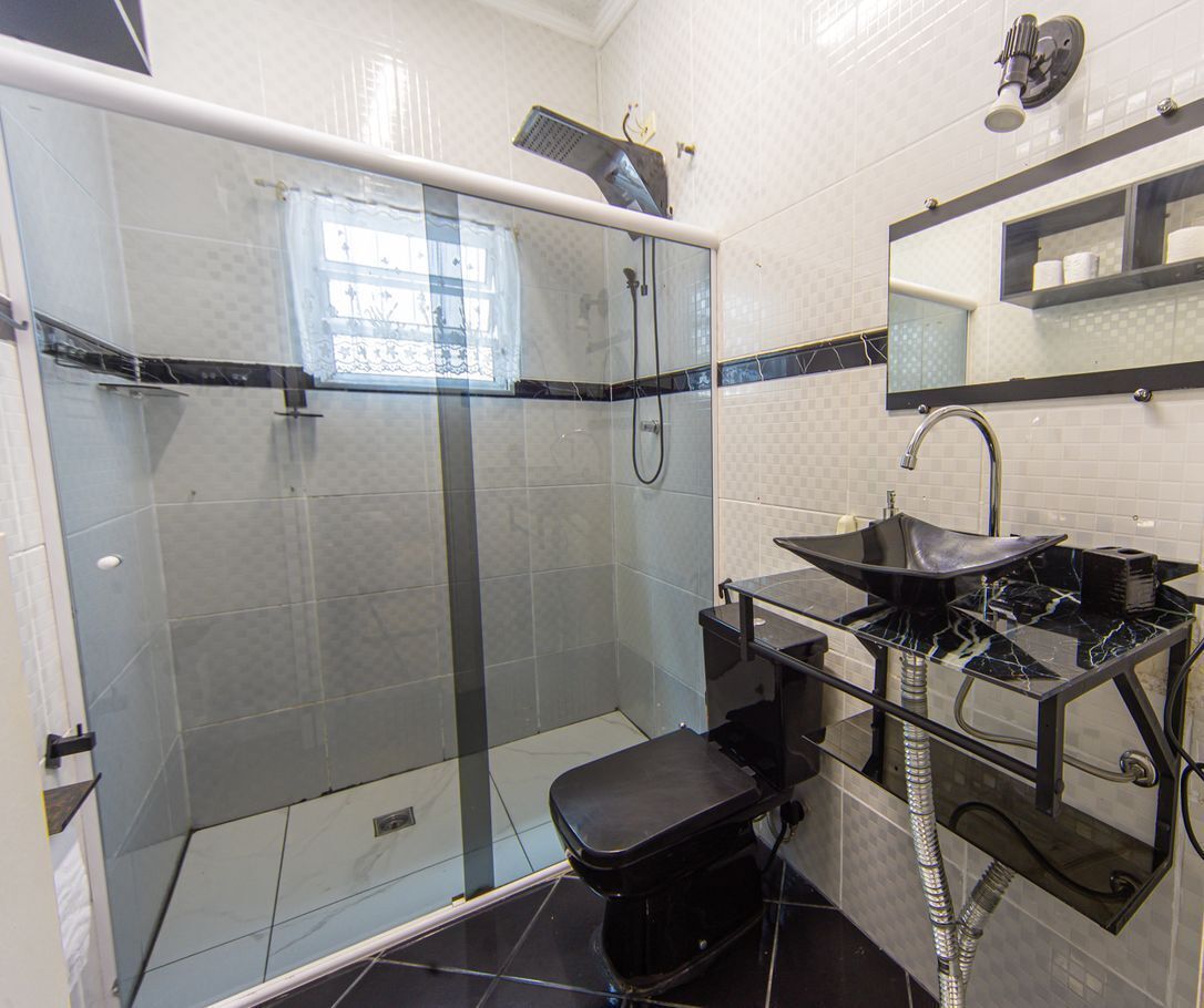 A modern bathroom with a glass-enclosed shower, a black sink with a marble countertop, and a mirror above the sink.