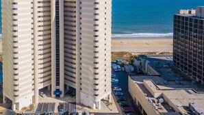 Un grand hôtel à plusieurs étages, doté d’un parking et offrant une vue sur la plage et l’océan.