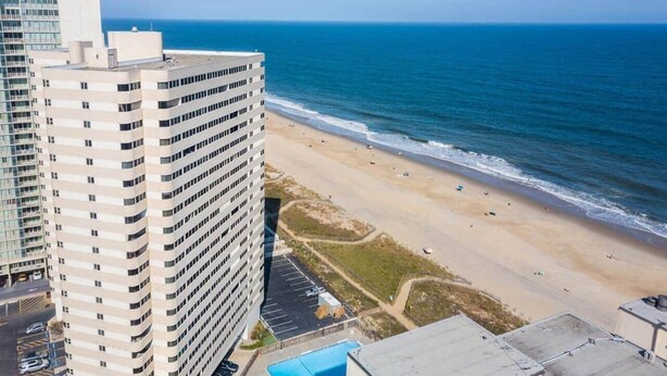 Un grand hôtel avec de nombreux étages, donnant sur une plage, et disposant d’un parking et d’une piscine.